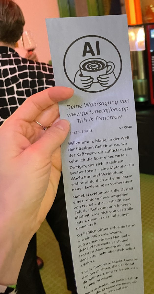 Eine Hand hält einen gedruckten Bon des Automaten mit Logo, Datum und einer Weissagung für Marie.